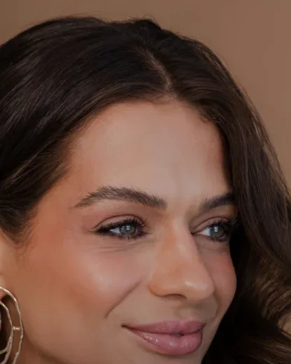 Bruna Thomé, de perto, sorrindo de leve e olhando para o lado